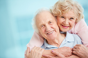 Elderly couple in warm embrace smiling with blue background